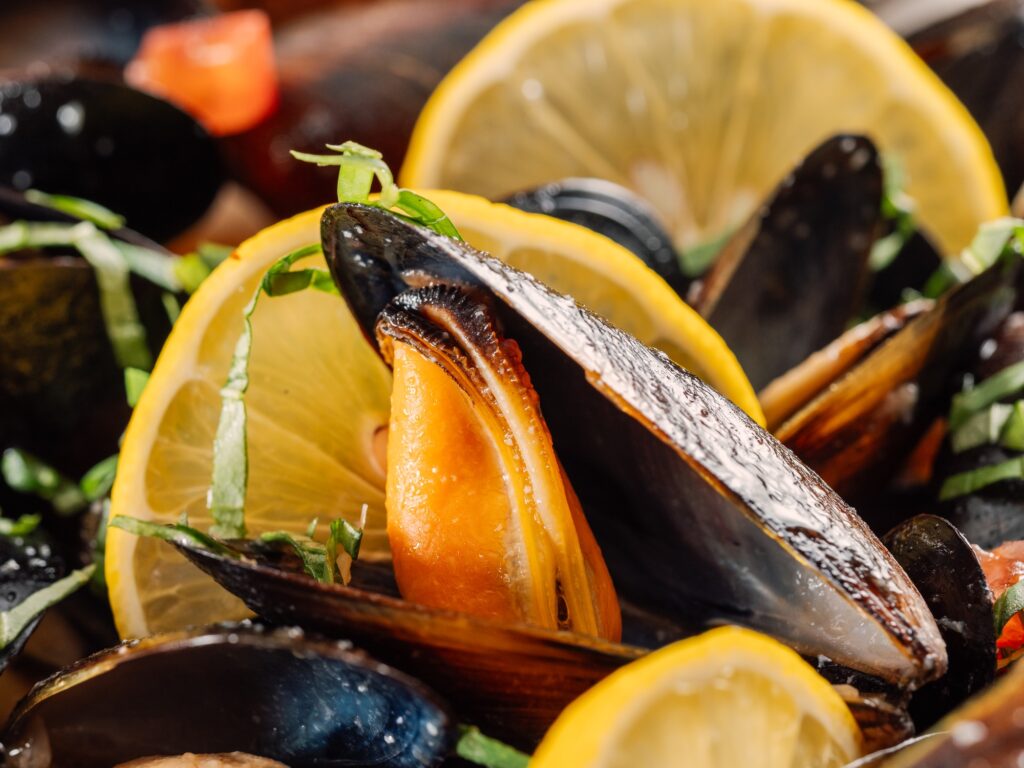 cooked mussels with lemon in white bowl