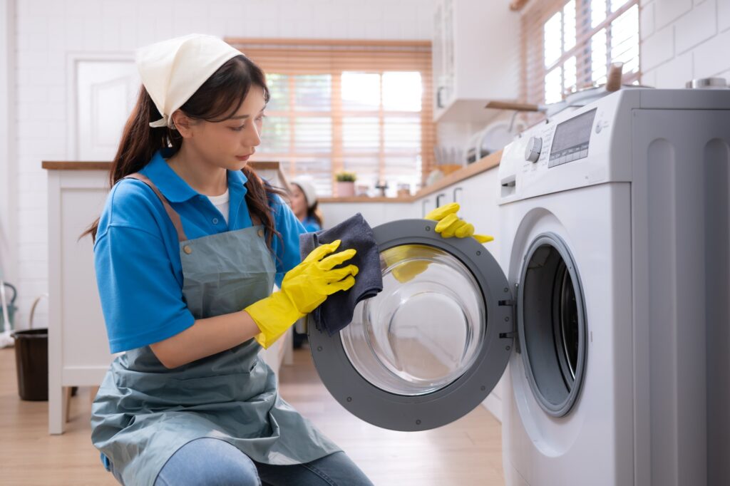 Asian young woman cleaning the washing machine in the kitchen. housework concept