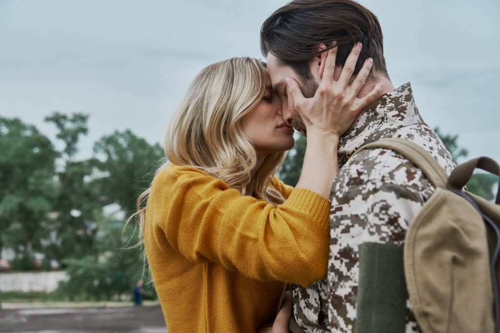 Beautiful young woman hugging and kissing her husband before his leaving on war