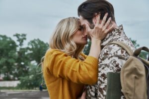 Beautiful young woman hugging and kissing her husband before his leaving on war