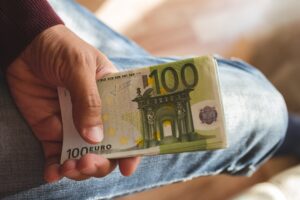 one hundred euro banknotes in tanned hand of man against the background of leg in jeans