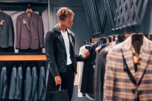 Young guy in modern store with new clothes. Elegant expensive wear for men
