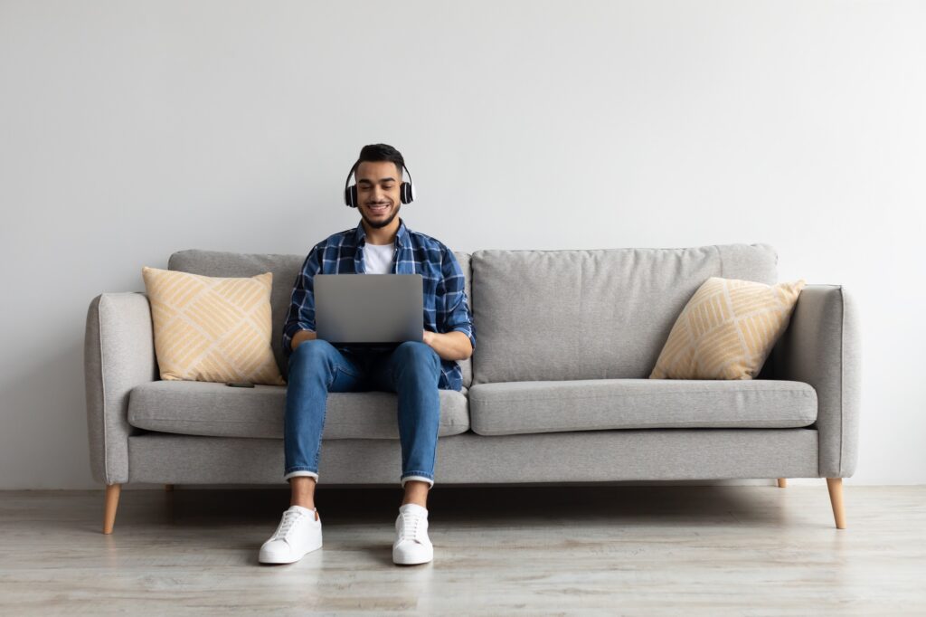 Smiling Arab man in headphones using pc at home