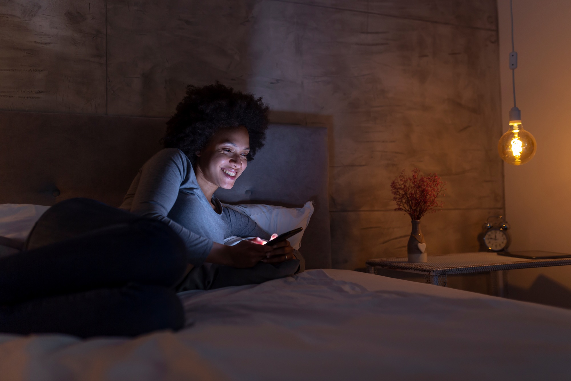 Woman lying in bed typing a text message